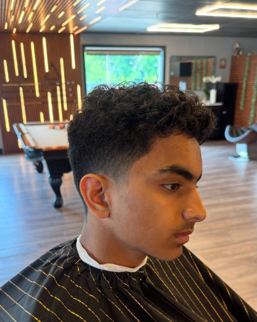 Low taper haircut with a curly top at X-Ecutive Barbershop in North Easton, MA
